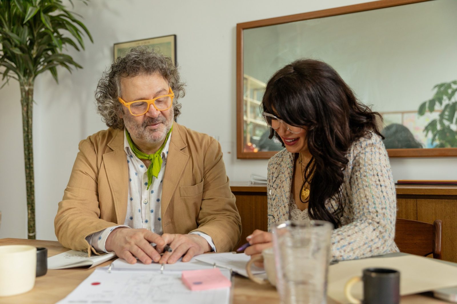 Two people go through a plan in a ring binder at a kitchen table, one holding a pen.